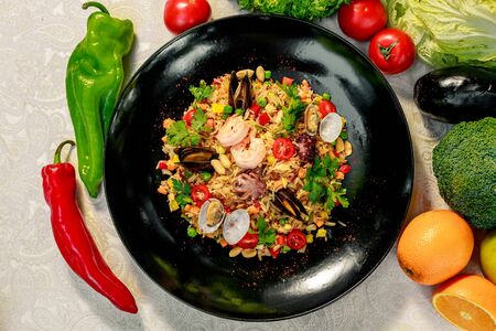 seafood risotto with octopus, shrimp and mussels with tomatoes healthy food in a white plate on a white tableの写真素材