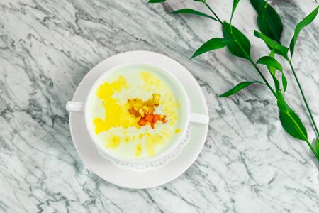 Breakfast, milk rice porridge with honey and dried fruits on a white plate, beautiful servingの写真素材