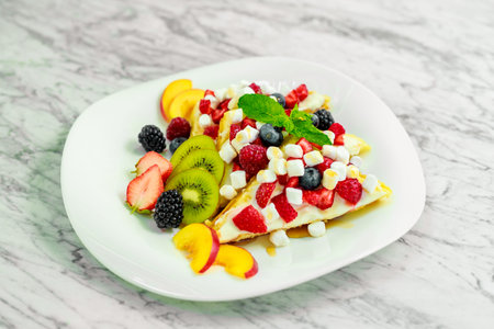 Belgian waffles with nuts, chocolate and fruit on a white plate, beautiful servingの写真素材