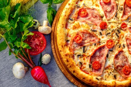 Delicious italian pizza served on table with ingredients cheese and vegetablesの写真素材