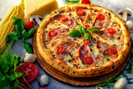 Delicious italian pizza served on table with ingredients cheese and vegetablesの写真素材