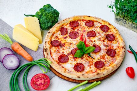 Delicious italian pizza served on table with ingredients cheese and vegetablesの写真素材