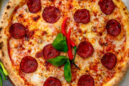 Delicious italian pizza served on table with ingredients cheese and vegetablesの写真素材
