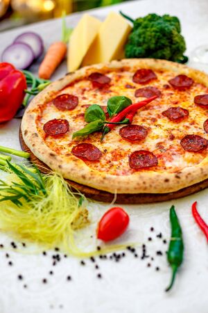 Delicious italian pizza served on table with ingredients cheese and vegetablesの写真素材