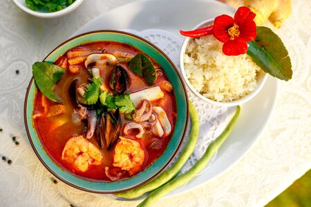 Thai soup tom yam with seafood (octopus, shrimps), herbs and vegetables served on the table with ingredients, healthy foodの写真素材