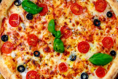 Delicious italian pizza served on table with ingredients cheese and vegetablesの写真素材