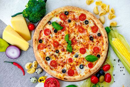 Delicious italian pizza served on table with ingredients cheese and vegetablesの写真素材