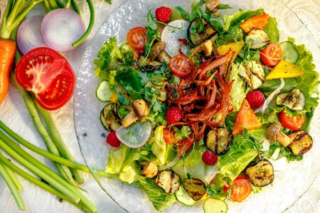 Fresh salad with dried meat, herbs and vegetables served on the table with the ingredients, healthy foodの写真素材