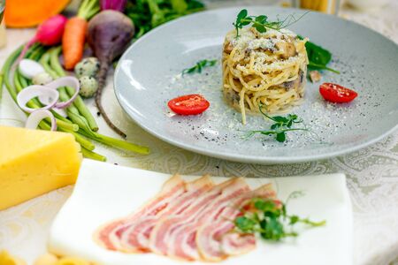 Italian pasta carbonara served on a table with ingredientsの写真素材