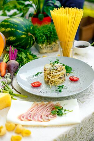 Italian pasta carbonara served on a table with ingredientsの写真素材