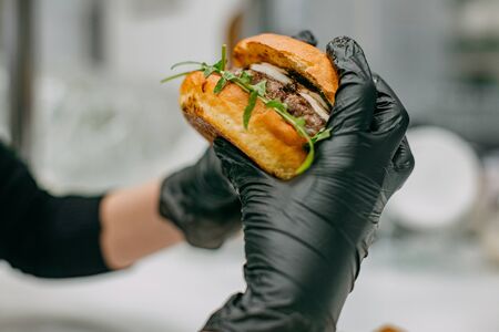 juicy burger with a cutlet in the hands in glovesの写真素材