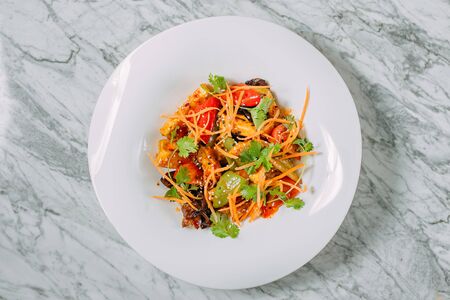 Vegetarian tomato, olives pepper salad in a white plate on a marble table, healthy foodの写真素材