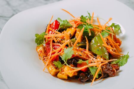 Vegetarian tomato, olives pepper salad in a white plate on a marble table, healthy foodの写真素材