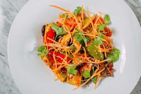 Vegetarian tomato, olives pepper salad in a white plate on a marble table, healthy foodの写真素材