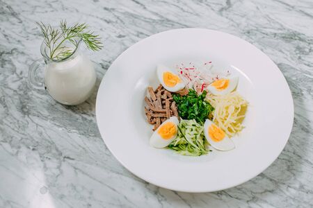 ingredients for cooking russian okroshka dish in a white plate on a marble tableの写真素材