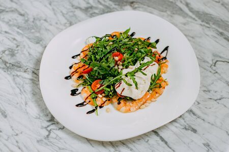 salad with shrimp, cheese and arugula in a white plate on a marble tableの写真素材