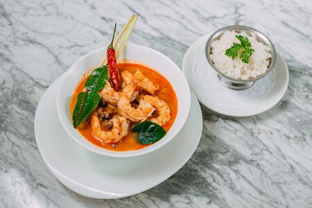 tom yum with shrimp and rice in a white plate on a marble tableの写真素材