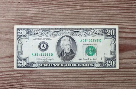 closeup of an old-style twenty-dollar bill isolated on wooden backgroundの写真素材