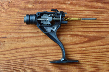 close-up of disassembled black reel for spinning isolated on wooden background