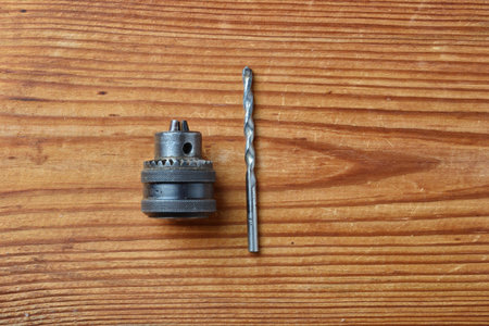 closeup of cam chuck and drill for electric drill isolated on wooden background