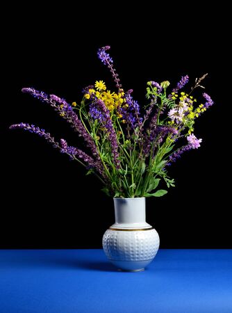 still life with bunch of wildflowers in a vintage white jug on a black backgroundの写真素材