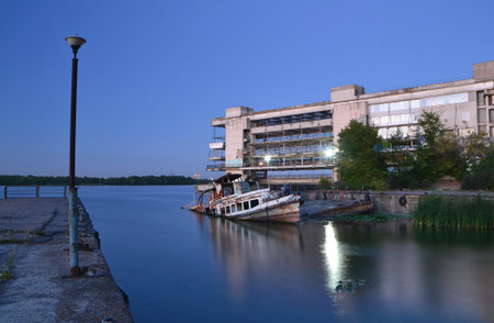 half-submerged old boat at the pier of an abandoned river stationの写真素材