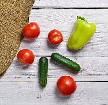 still life with tomatoes, cucumbers, pepper on an old wooden light rustic table with an old bagの写真素材