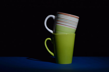 two cups nested one in one on blue desk and isolated on black background, copy spaceの写真素材