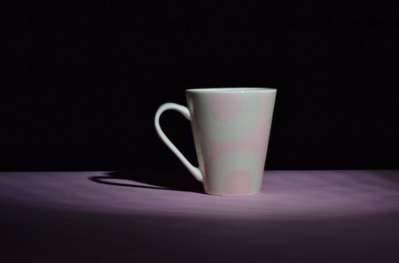 pink ceramic cup in the darkness on pink desk and isolated on black background, copy spaceの写真素材