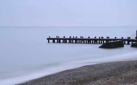 old pier and beach for meditation in cloudy day, long exposure, place for textの写真素材