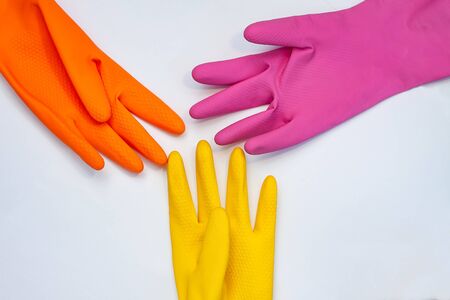 orange, yellow and crimson  gloves for cleaning on a grey backgroundの写真素材