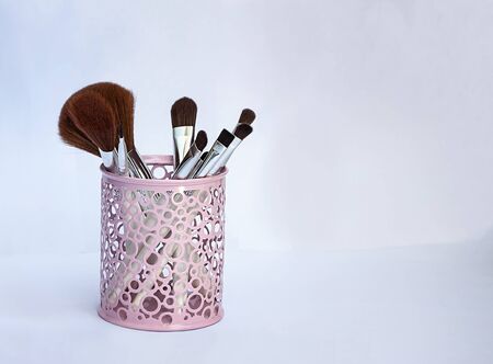 Set of makeup brushes in a pink iron glass on a light backgroundの写真素材