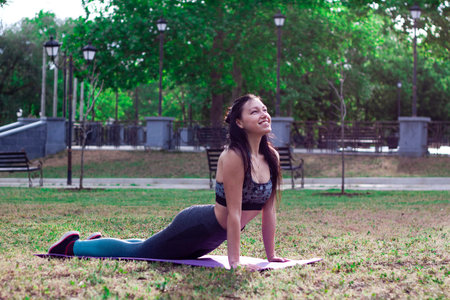 Beautiful  smiling brunette girl is  doing yoga Cobra Pose Bhujangasana.  Concept of sport の写真素材