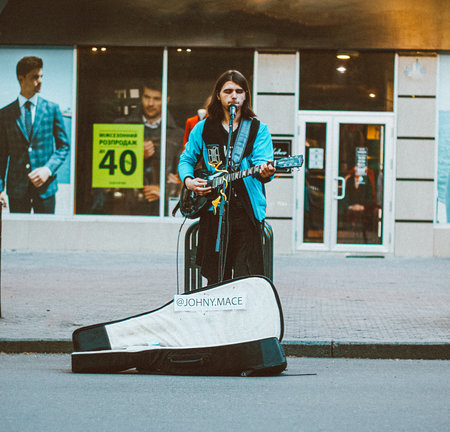 Nikolaev, Ukraine- June 6, 2020:  street musician with guitar sings songs  in the microphone on the main city street Sobornaのeditorial素材