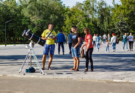 Nikolaev, Ukraine- June 6, 2020: a man with a telescope tells the details to his clients - a man and a woman on the square 8 Prichal   in  a sunny dayのeditorial素材
