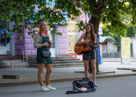 Nikolaev, Ukraine- June 6, 2020: 2 girls (street musicians )  with guitar sings songs on the main city street Sobornaのeditorial素材