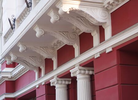 One multi-storey building with the red wall which is  decorated with beautiful white stucco molding. Summer day is outsideの写真素材