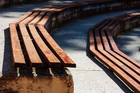 2 rows of old wooden benches are partially lit by the summer sunの写真素材