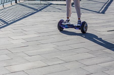 Young girl on the gyro-board on the square  in  a sunny day  has a good time. Close-up picture の写真素材