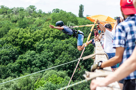 Ivanovsky Bridge, Ukraine - June 21, 2020: Concept of Extreme Sports and Fun. A man is  doing rope jumping from the bridge. He is happy to make a dream come true. All equipment is very firmly fixedのeditorial素材