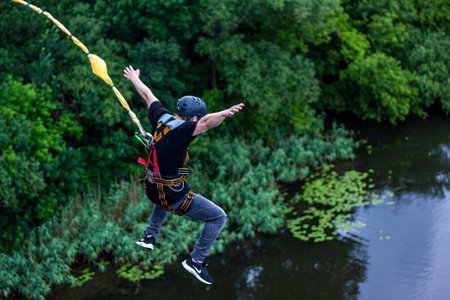 Ivanovsky Bridge, Ukraine - June 21, 2020: Concept of Extreme Sports and Fun. A man is  doing rope jumping from the bridge. He is happy to make a dream come true. All equipment is very firmly fixedのeditorial素材