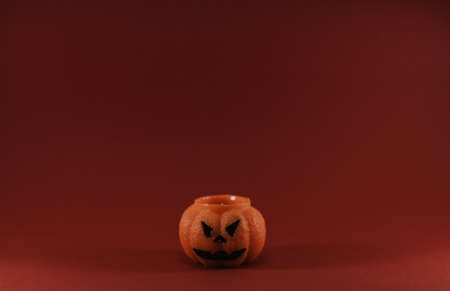 One scary orange pumpkin shaped candle, isolated on red background, space for text. Tradition Happy Halloween concept.の写真素材