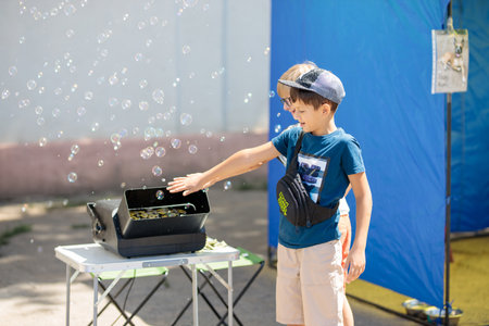 Nikolaev, Ukraine- August 15, 2020: volunteer exhibition of stray dogs. Ð¡hildren play with a machine that makes soap bubbles. They are happy and corious. Hot summer weather.Concept of happines, restのeditorial素材