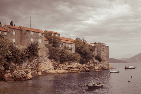 Sveti Stefan, Montenegro- September, 2021: summer sunset on Beach. Resort includes the islet of Sveti Stefan and part of the mainland. Ancient houses and plants from medieval times. Dark brown toningのeditorial素材