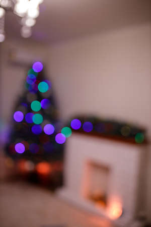 New Year tree and home decorated in the evening. Gift boxes and red socks with present near white brick fireplace. Concept - Upcoming 2022 New Year. Intentionally blurredの写真素材