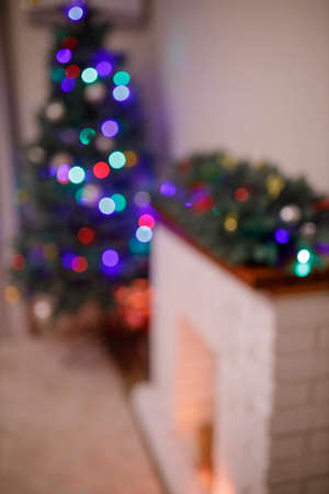 New Year tree and home decorated in the evening. Gift boxes and red socks with present near white brick fireplace. Concept - Upcoming 2022 New Year. Intentionally blurredの写真素材