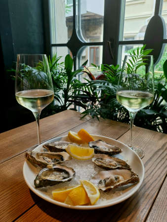 testing of oysters seafood with lemon on ice cubes, in the restaurant. Romantic with two glasses of white wineの写真素材
