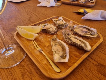 testing of oysters seafood, with glass of white wine on a wooden table, outside restaurant with a...