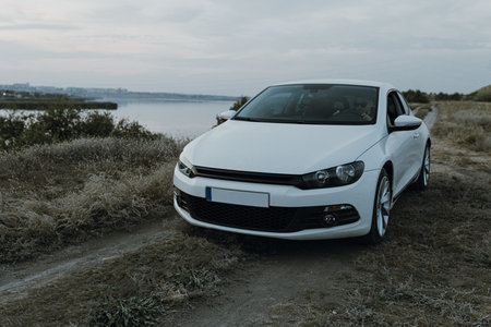 Modern luxury white sedan 2-doors sport car at the sunset outdoors. Fresh weekend out of city near...