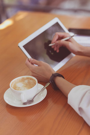 Portrait happy young office assistant working remotely online sitting with laptop, tablet and coffee outside on terrace making notes on laptop and checking smartphone. remote freelance successful jobの写真素材